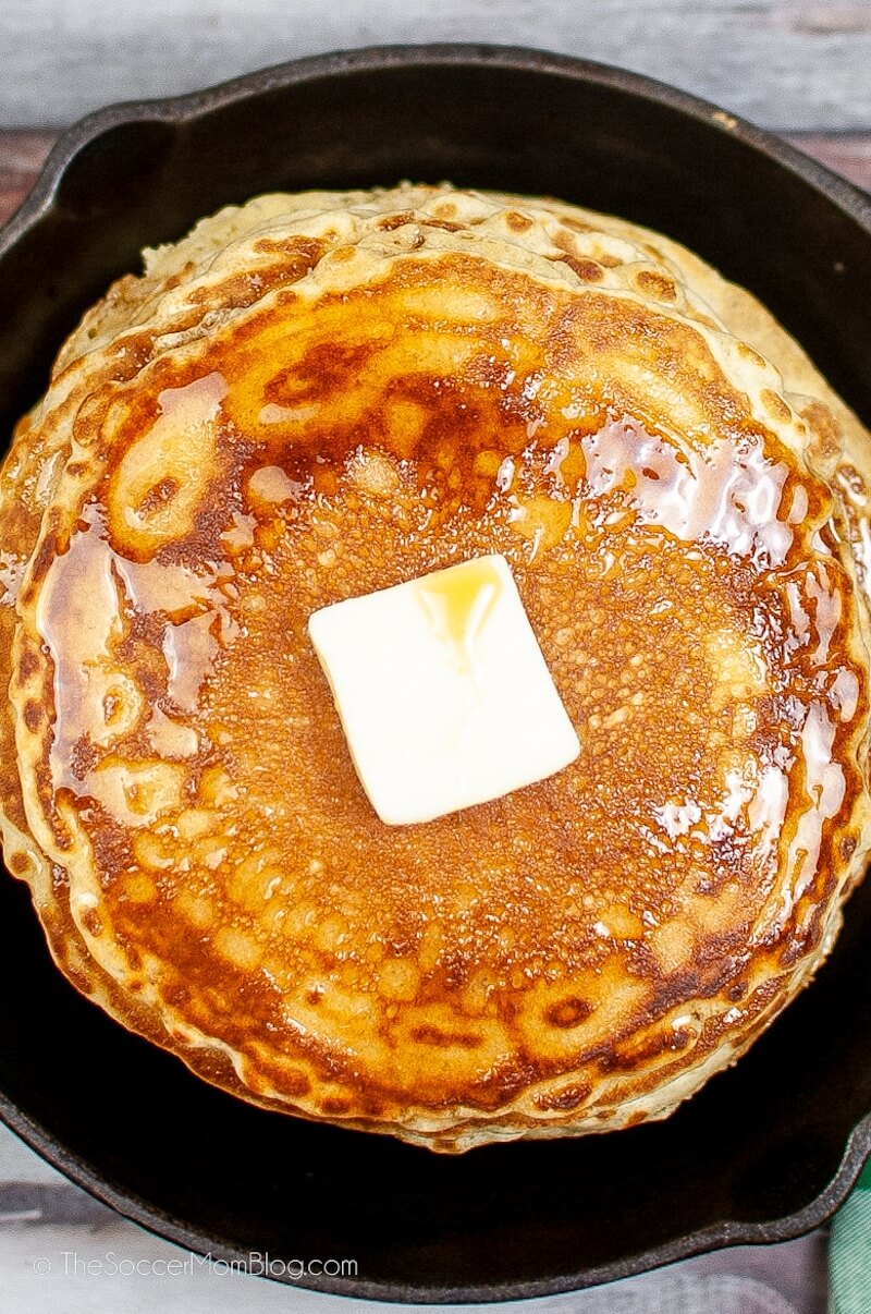 top down view of a golden brown pancake topped with butter and syrup