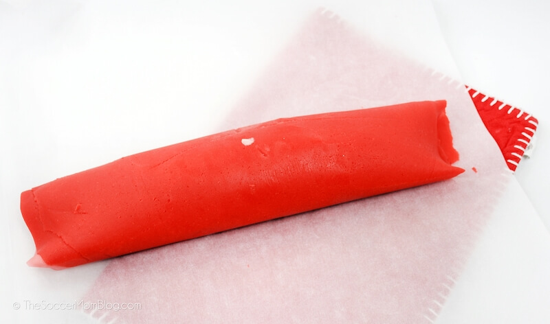 roll of red cookie dough on parchment paper