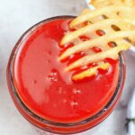 Dipping a waffle fry in a jar of homemade sweet & sour sauce