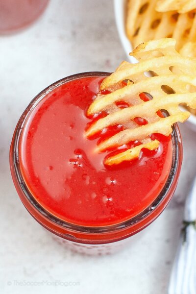 Dipping a waffle fry in a jar of homemade sweet & sour sauce