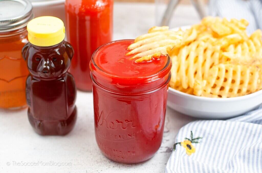 container of honey, jar of red sweet & sour sauce, and bowl of waffle fries