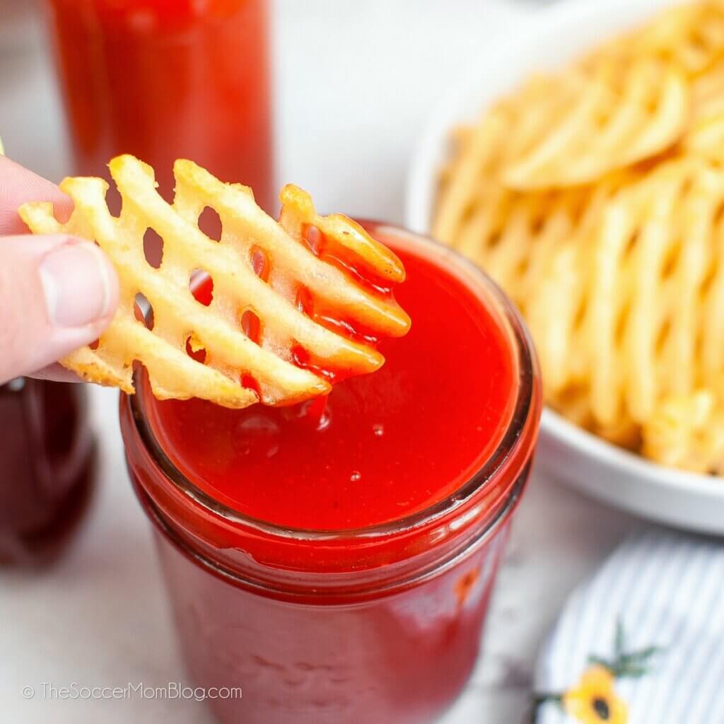 dipping a waffle fry in a jar of homemade red Polynesian sauce