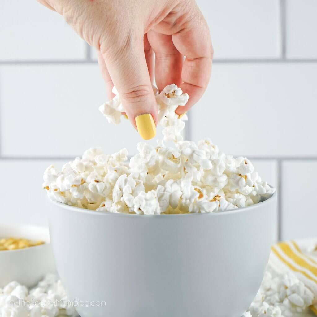 A hand taking popcorn from a bowl