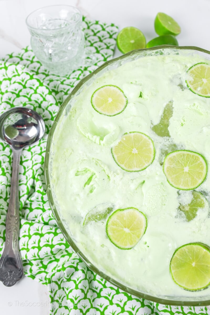 bowl of green punch with sherbet and limes on top