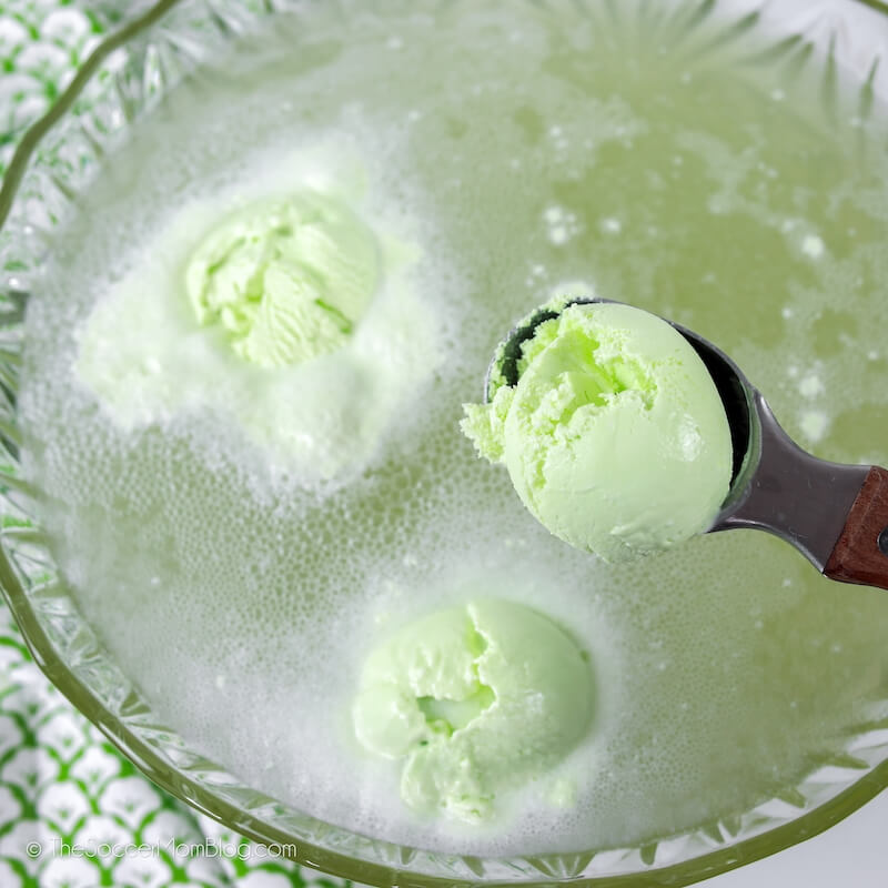 adding scoops of lime sherbet to a bowl of punch