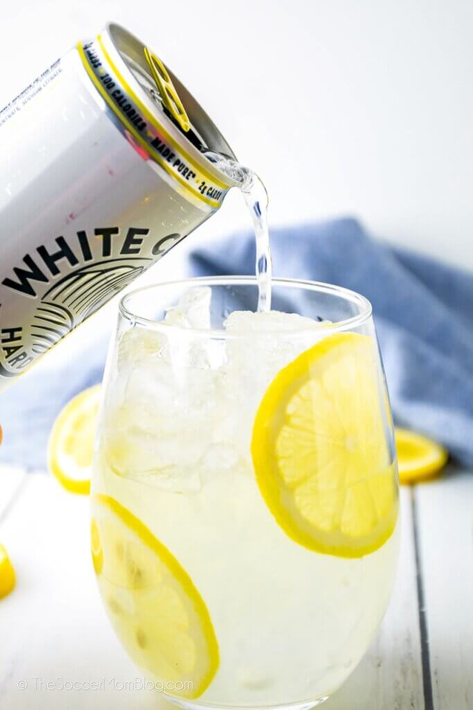 pouring white claw seltzer into a lemonade cocktail