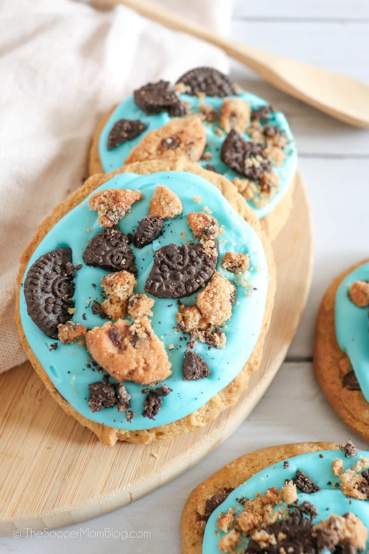 close up of a chocolate chip cookie with blue icing and cookies on top