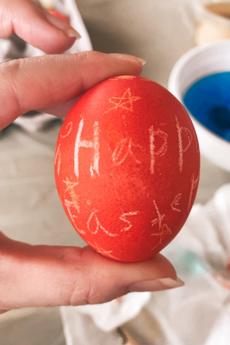 holding a red decorated Easter egg