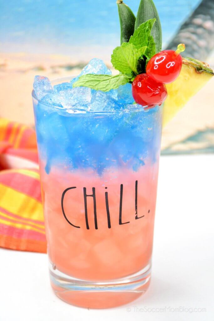 layered tropical Blue Hawaiian cocktail with beach background