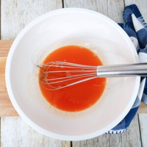 stirring orange jello liquid in mixing bowl