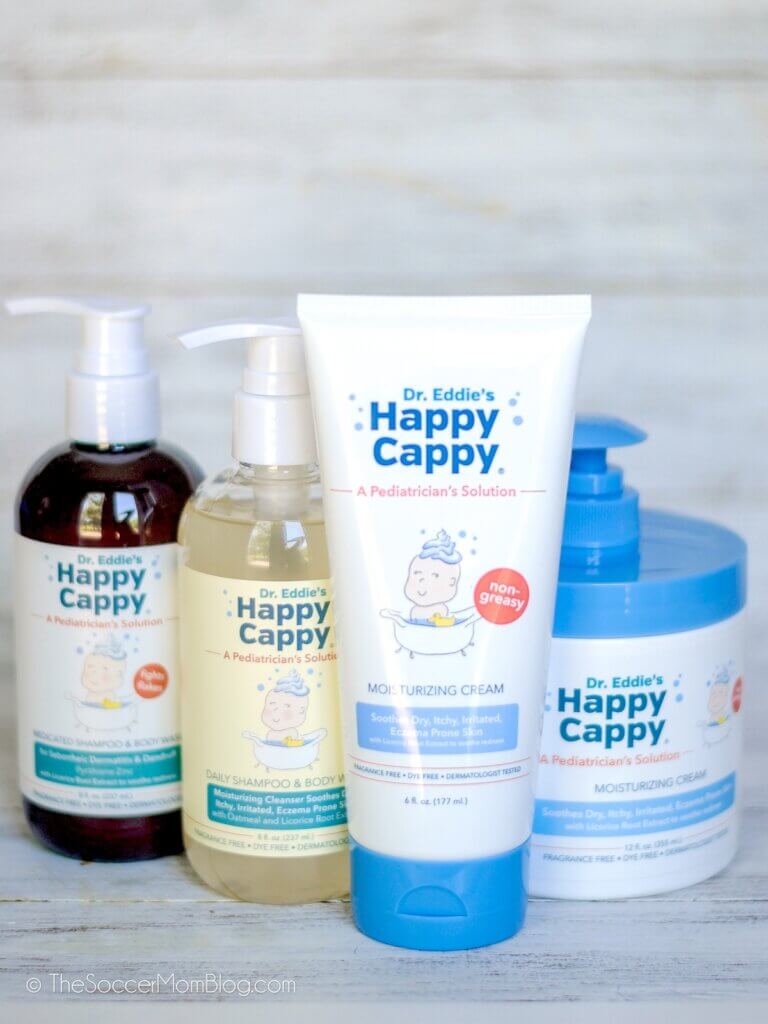 Happy Cappy hair and skin products for babies on wooden backdrop