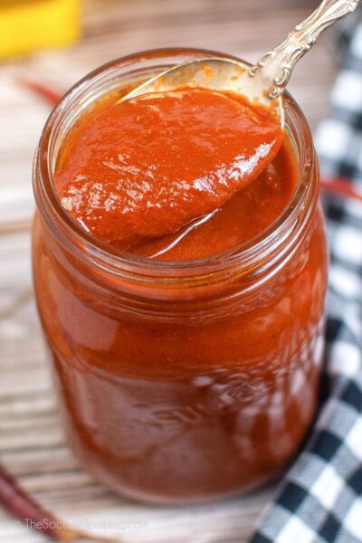 A spoon of Red Enchilada Sauce out of a jar