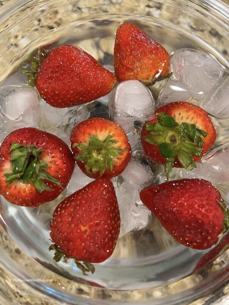 strawberries soaking in a bowl of ice water