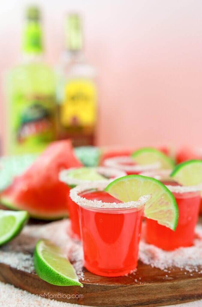 watermelon margarita jello shots with tequila bottle in background