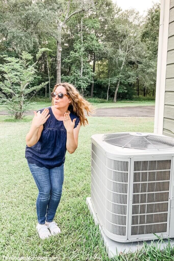 woman standing next to AC with hair blowing