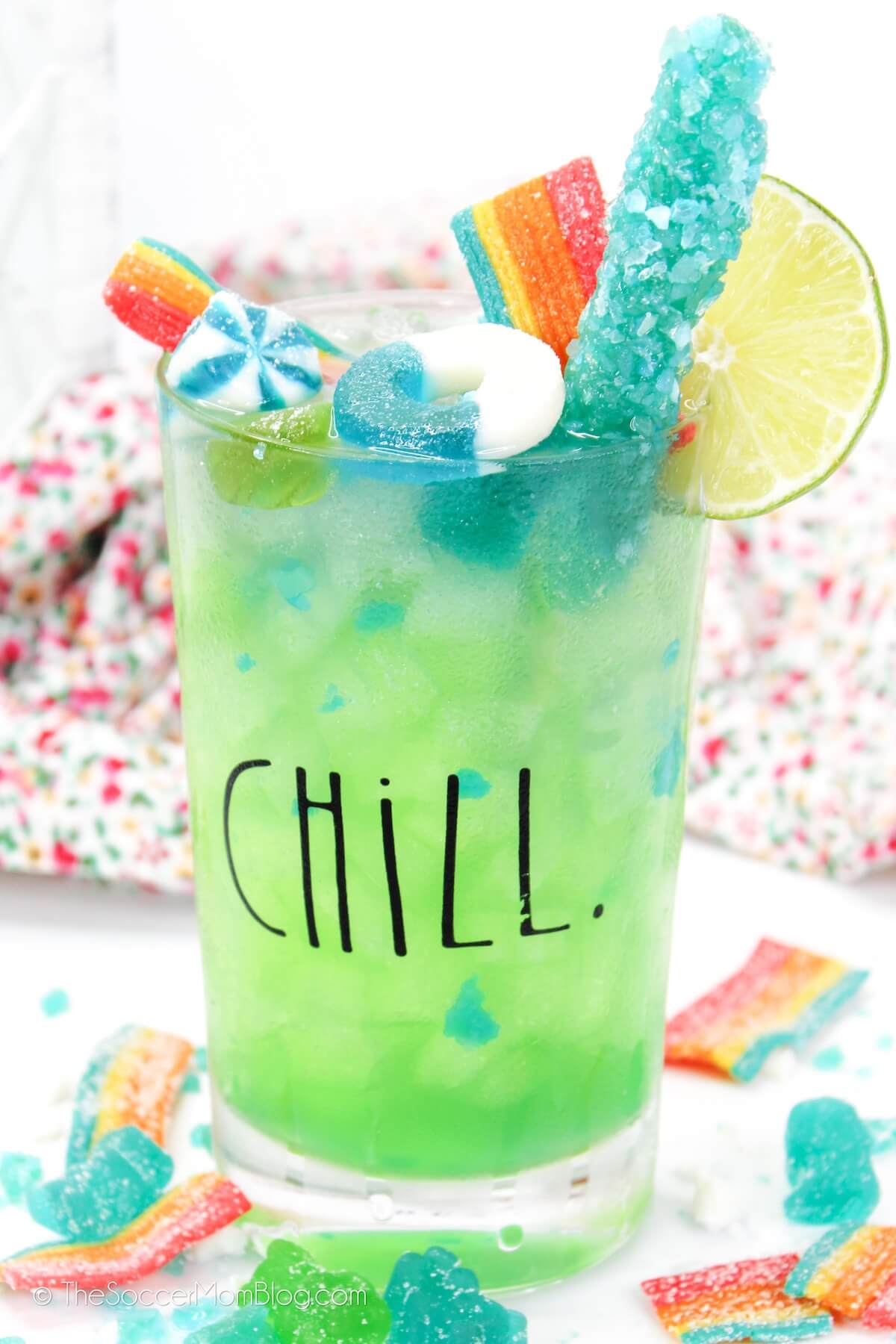 bright blue green cocktail topped with rock candy and gummies