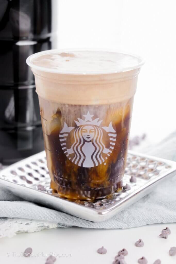 A Copycat Starbucks Chocolate Cold Brew Cup on a metal tray, surrounded by chocolate chips