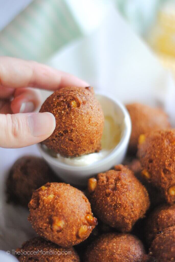 dipping a hush puppy into butter