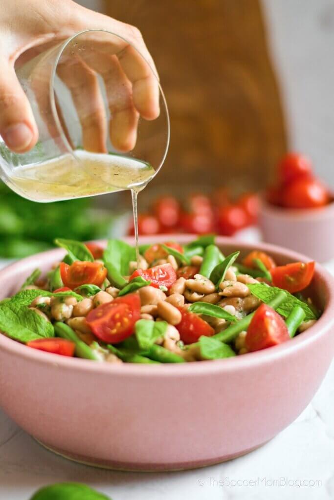 Pouring olive oil dressing on a bean salad