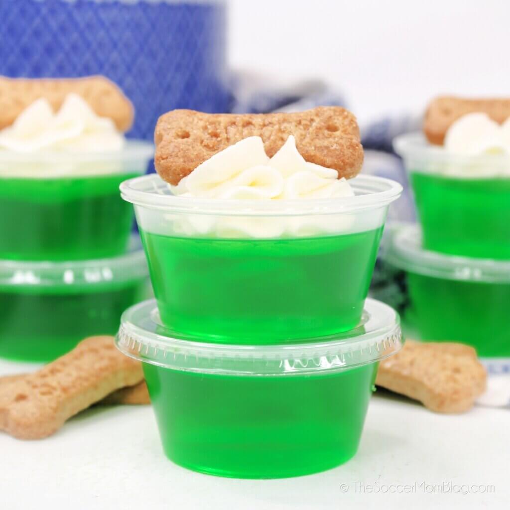 green jello shots topped with whipped cream and a Scooby Snack cookie
