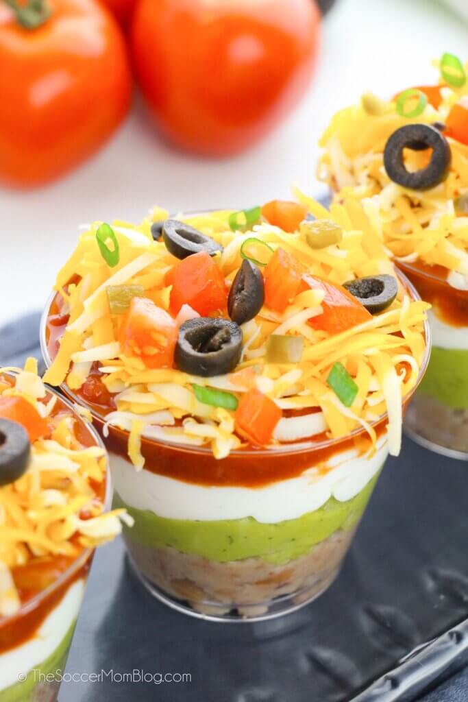 close up of a tray of layered taco dip cups