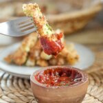 dipping a crispy zucchini fry in ketchup