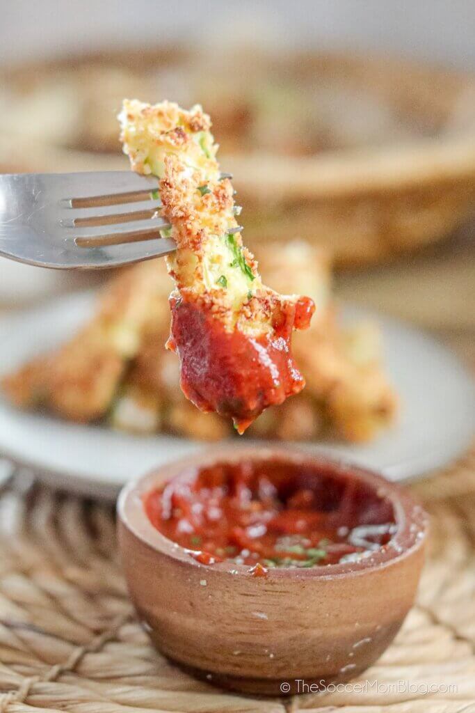 Air Fryer Zucchini Fry on fork, dipped in spicy ketchup