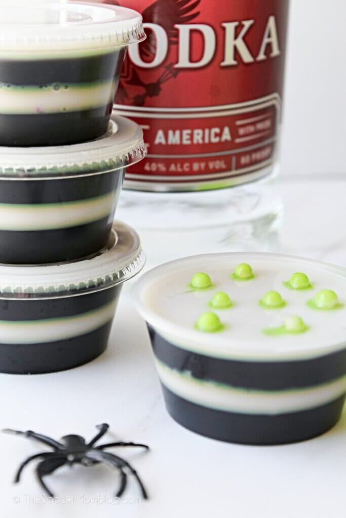 Four Beetlejuice Jello Shots stacked with a plastic spider decoration