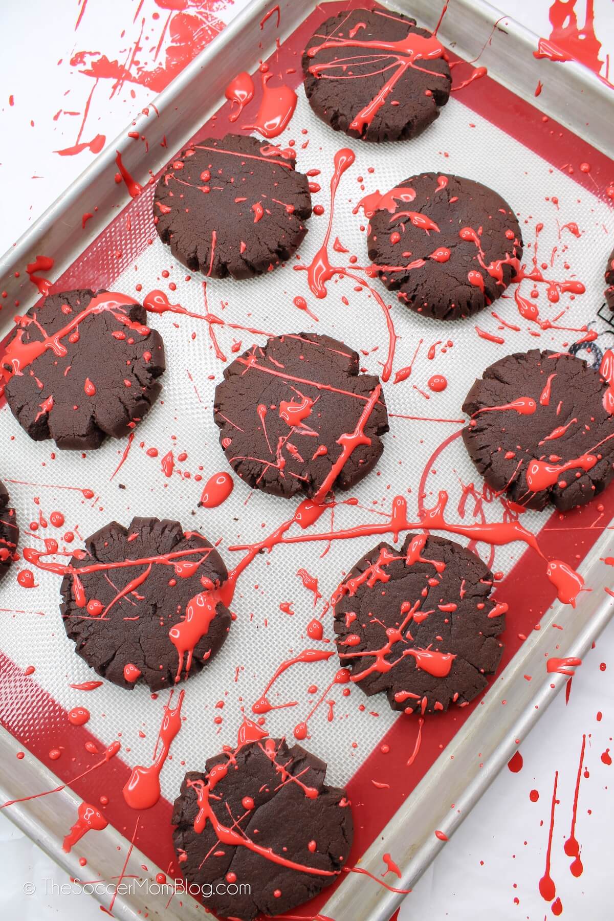 tray of chocolate cookies with splattered red frosting
