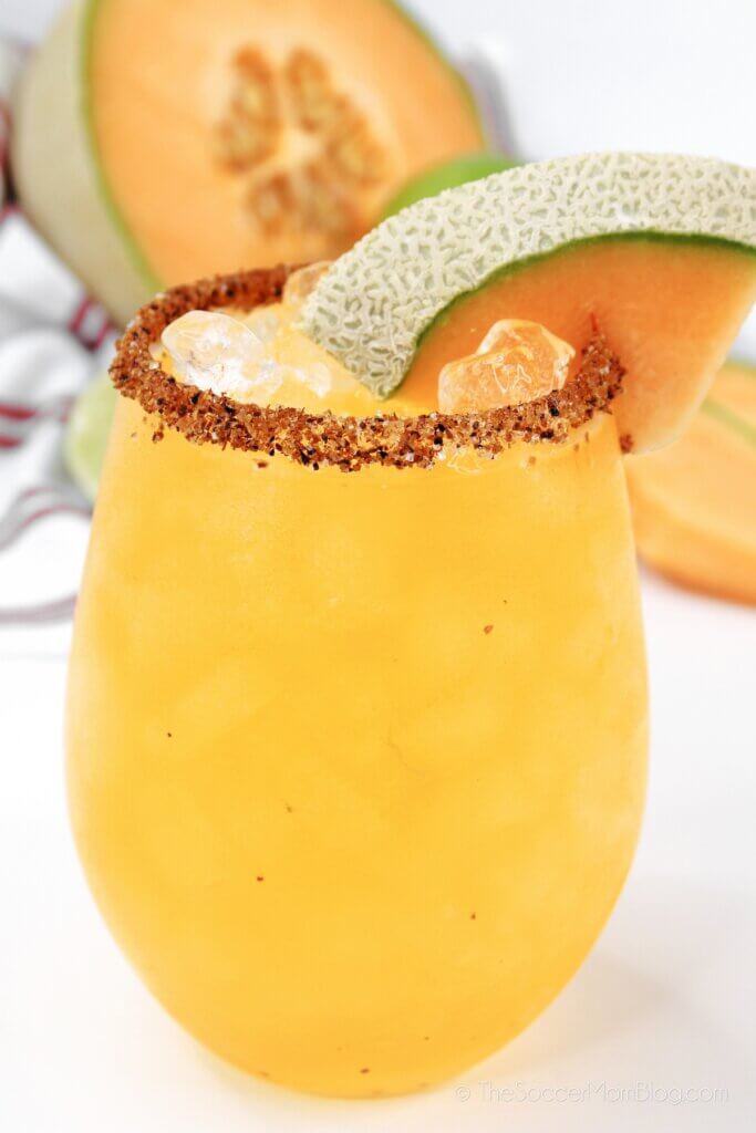 Bright orange Cantaloupe Margarita with Tajin on rim of glass