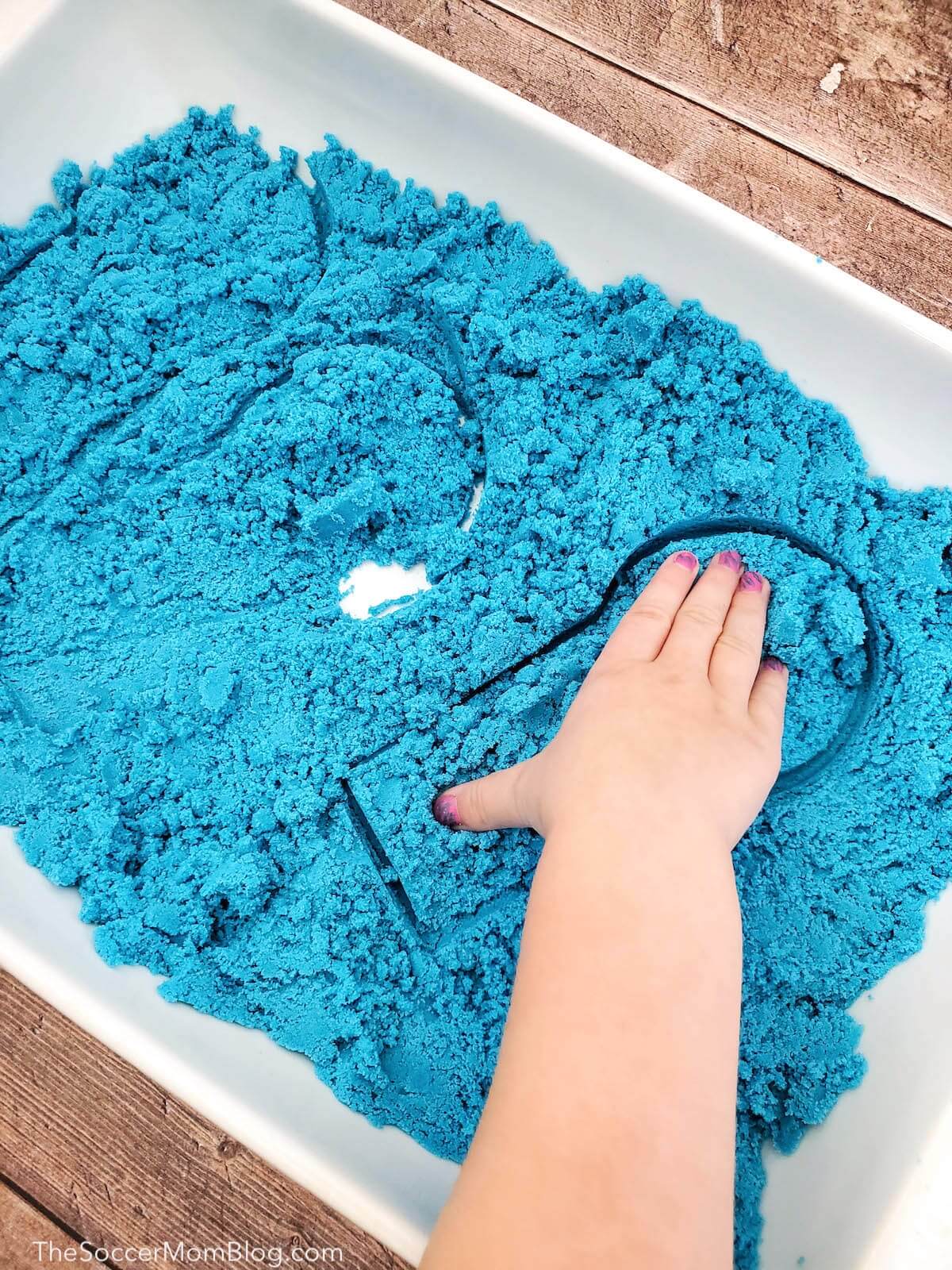 child playing with blue play sand