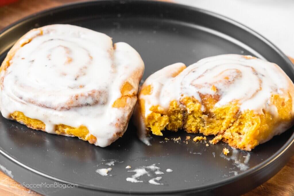 Two Pumpkin Cinnamon Rolls, one with bite missing