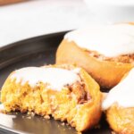 Three Pumpkin Cinnamon Rolls with a bite out of one