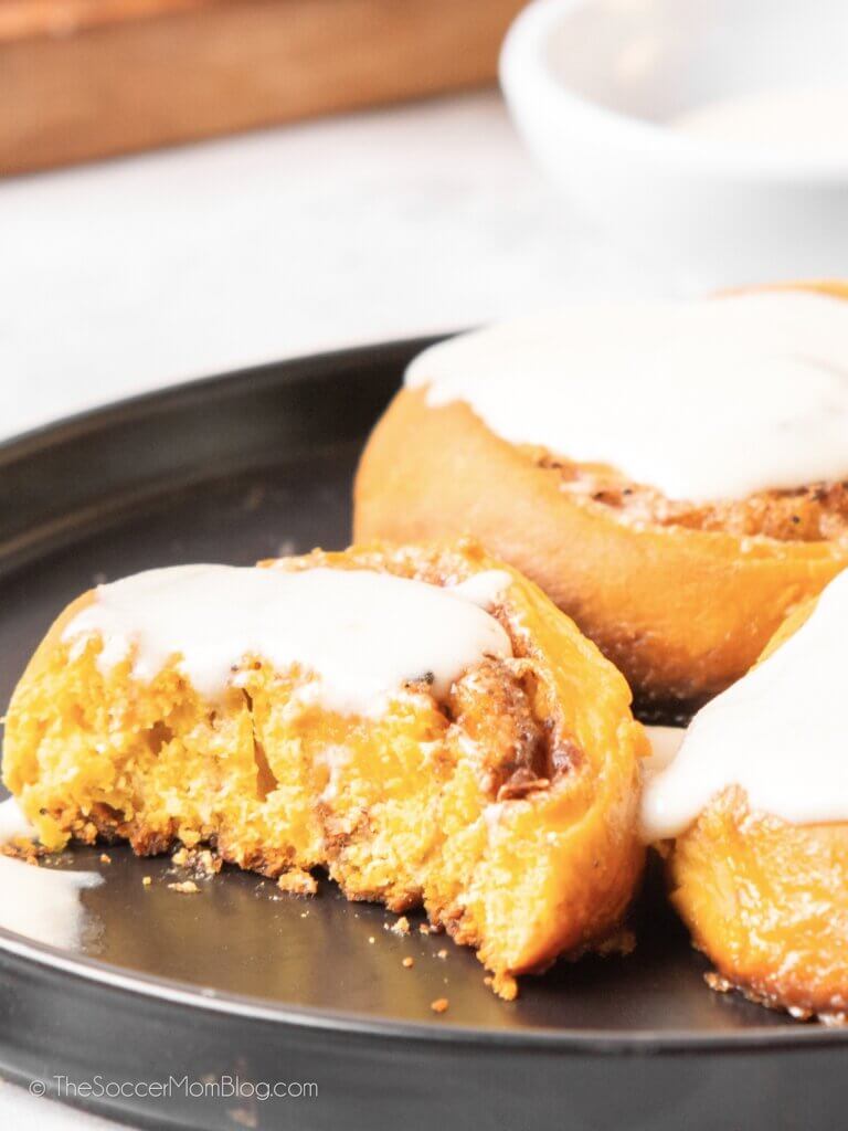 Three Pumpkin Cinnamon Rolls with a bite out of one