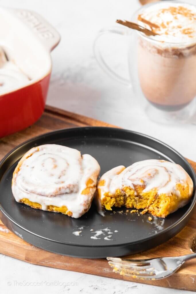 Two Pumpkin flavored Cinnamon Rolls, one with a bite out of it