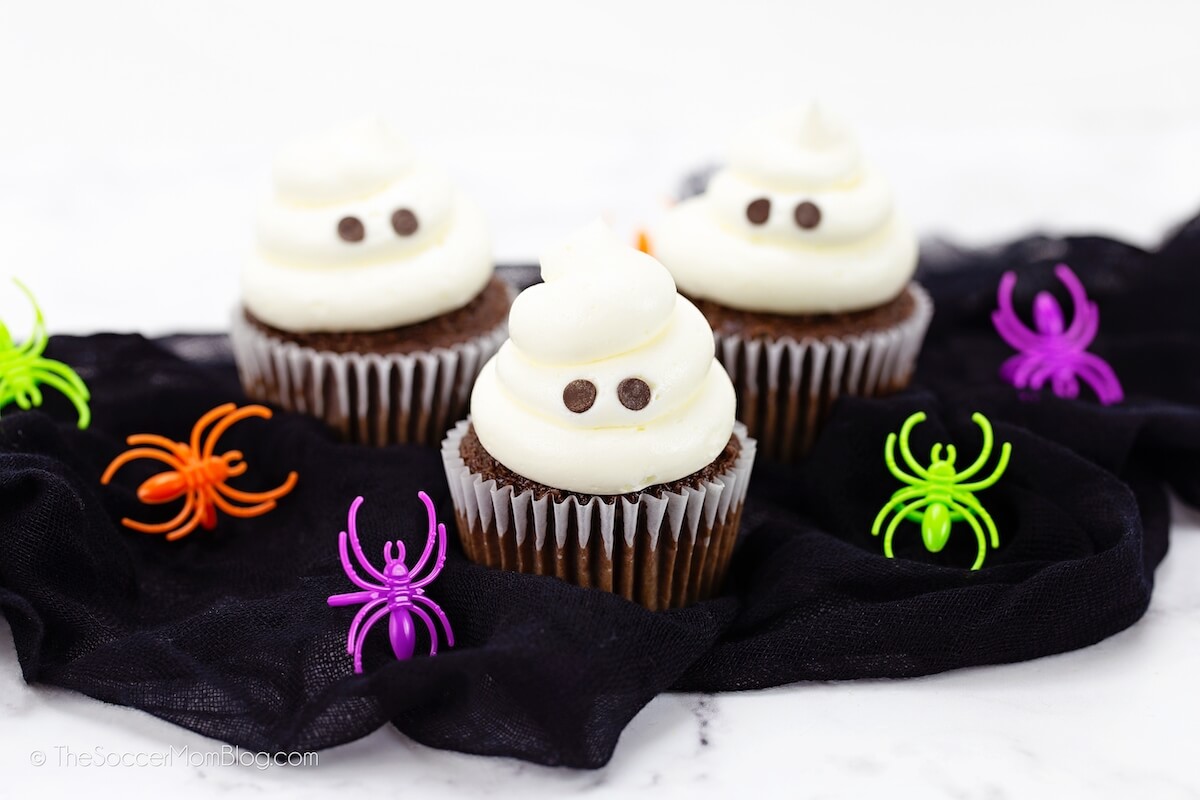 3 ghost cupcakes with neon spiders around them