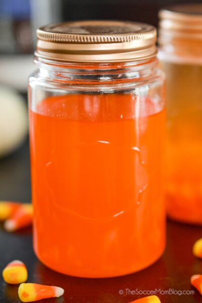 mason jar with bright orange moonshine and candy corn