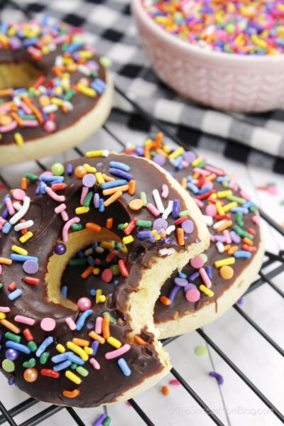 cookies decorated to look like chocolate sprinkle donuts, one with a bite missing