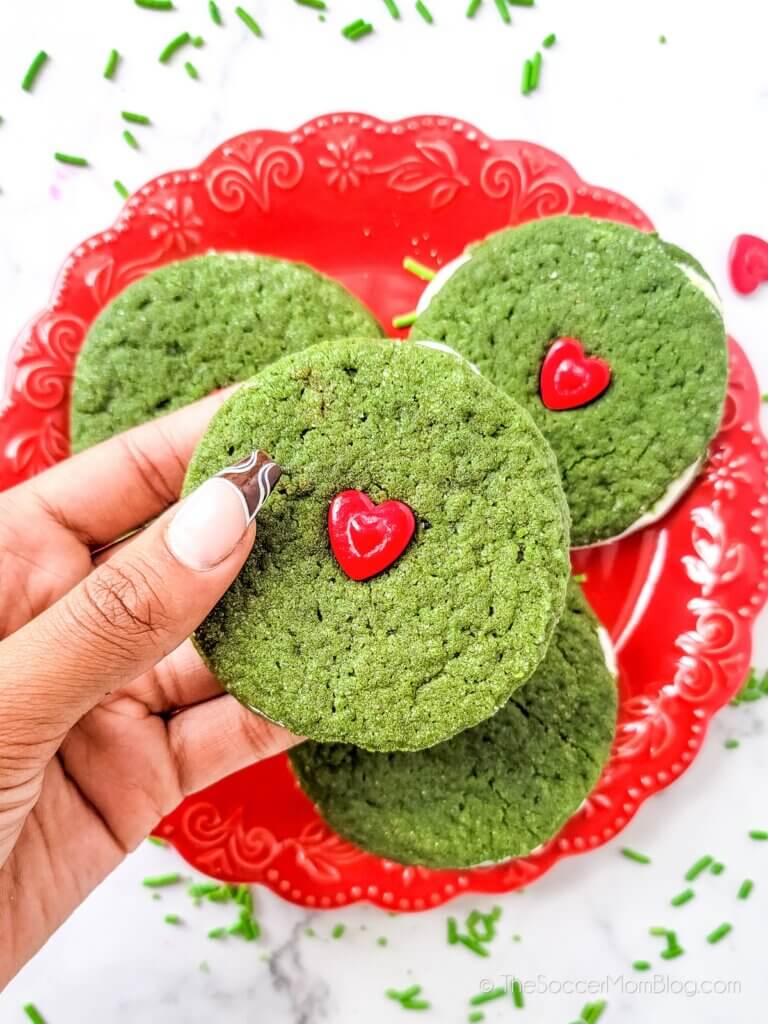 One Grinch Ginger Cookie Sandwich being held above a plate