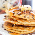 stack of chocolate chip pancakes with muffin mix in background