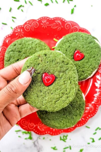 One Grinch Ginger Cookie Sandwich being held above a plate