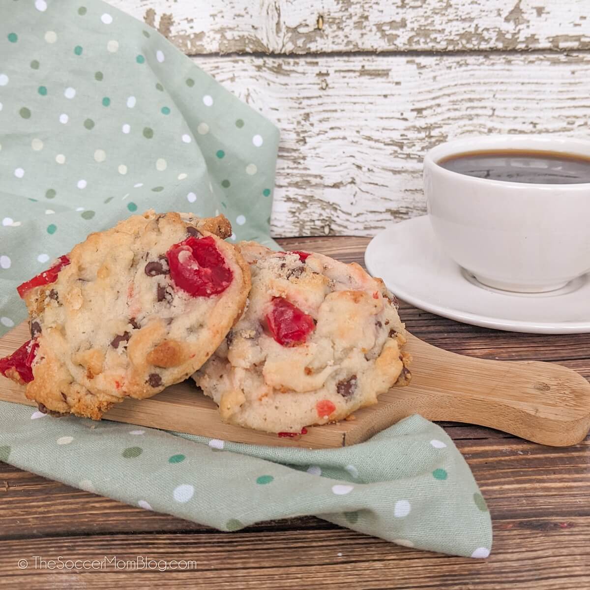Chocolate chip cherry cookies sitting on a wooden cutting board