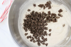 adding chocolate chips to a mixing bowl of cheesecake batter