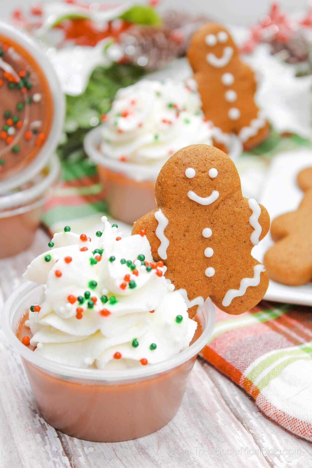 gingerbread jello shots decorated with whipped cream and mini gingerbread man cookie