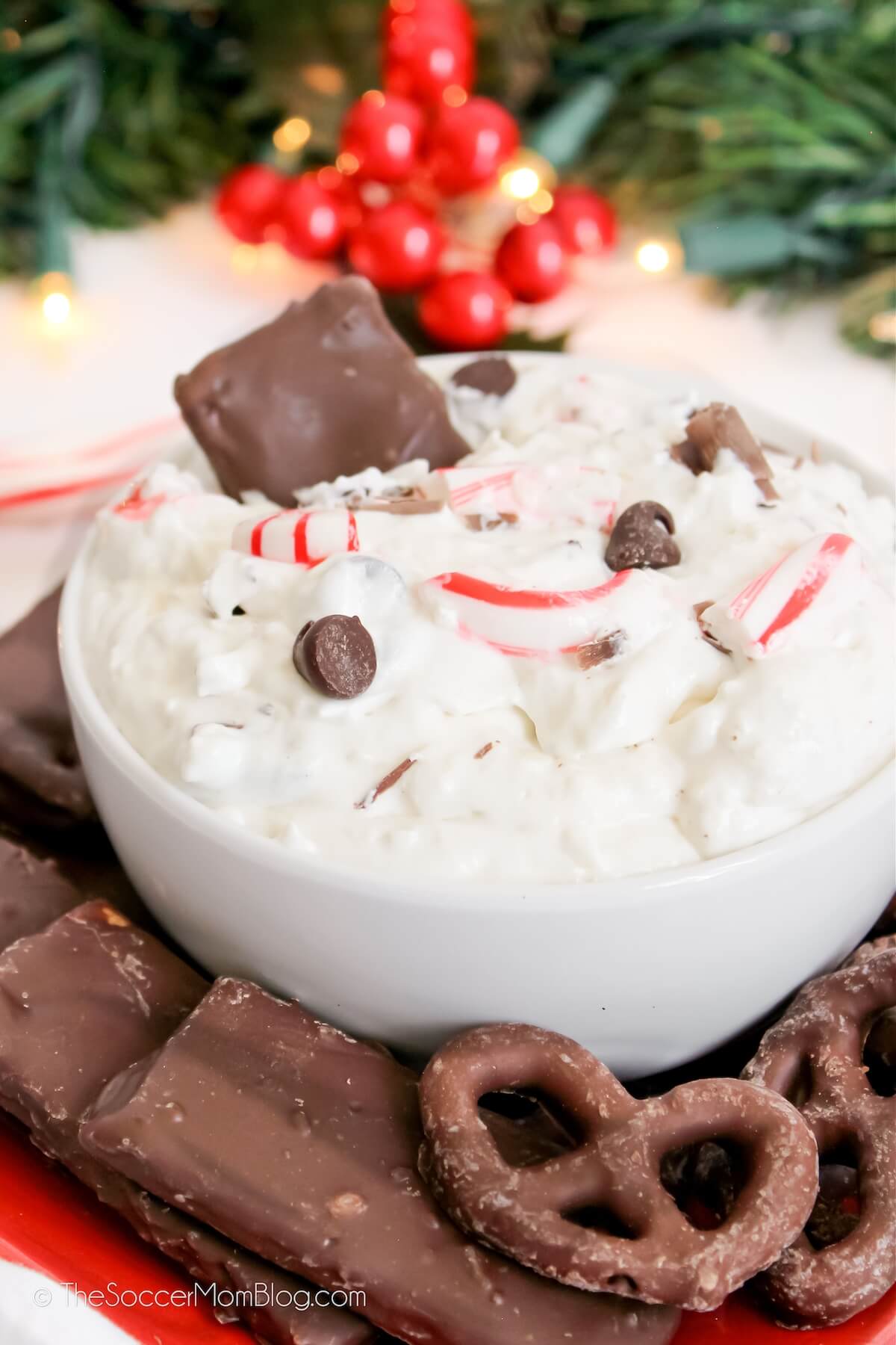 bowl of peppermint bark cheesecake dip surrounded by chocolate covered pretzels