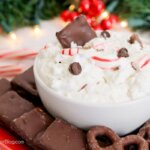 bowl of holiday cheesecake dip with chocolate chips and peppermint pieces