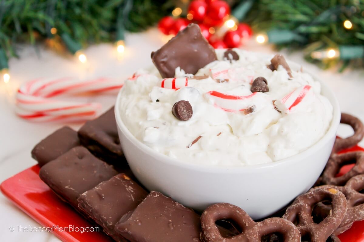 bowl of holiday cheesecake dip with chocolate chips and peppermint pieces