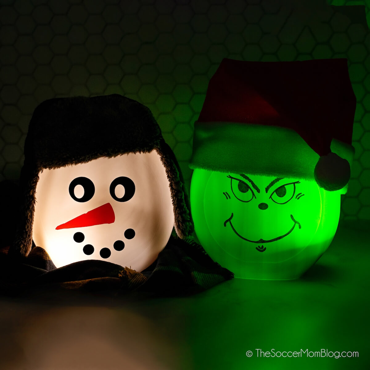 Grinch and snowman Christmas lanterns made from laundry pod containers, illuminated in dark