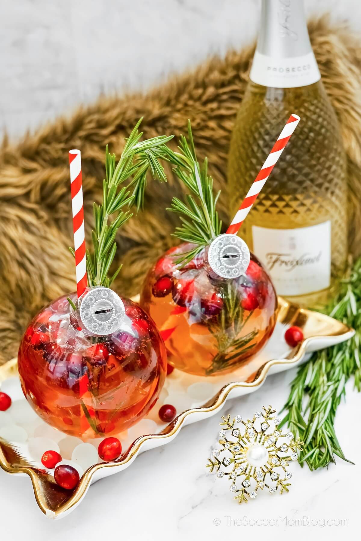 two clear ornaments filled with a Christmas mimosa drink