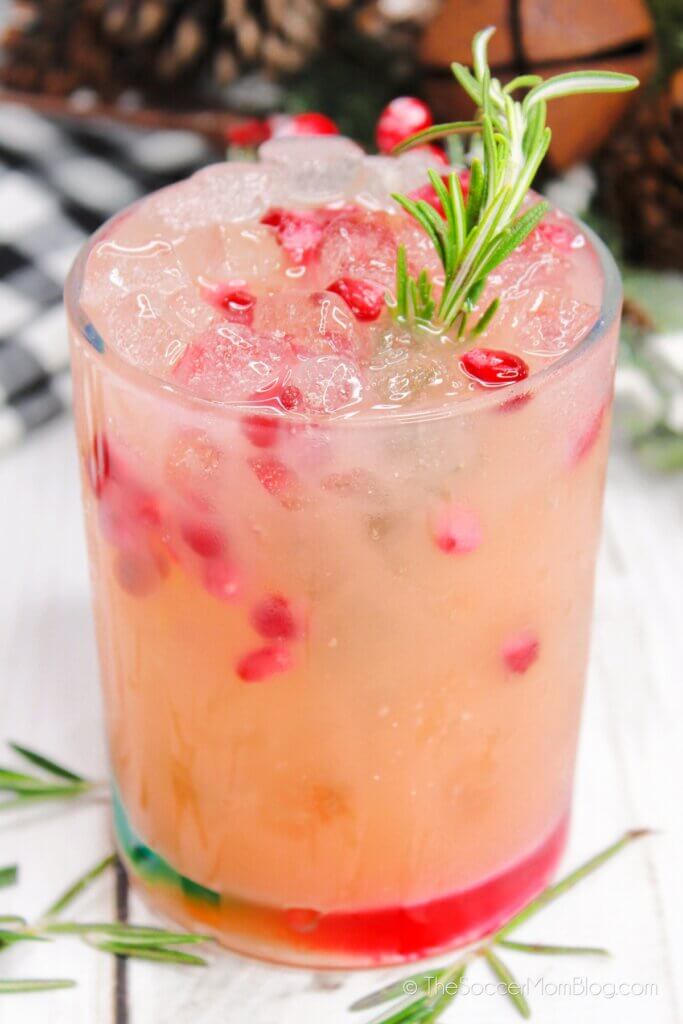 close up of a paloma tequila cocktail made with grapefruit juice, pomegranate, and rosemary